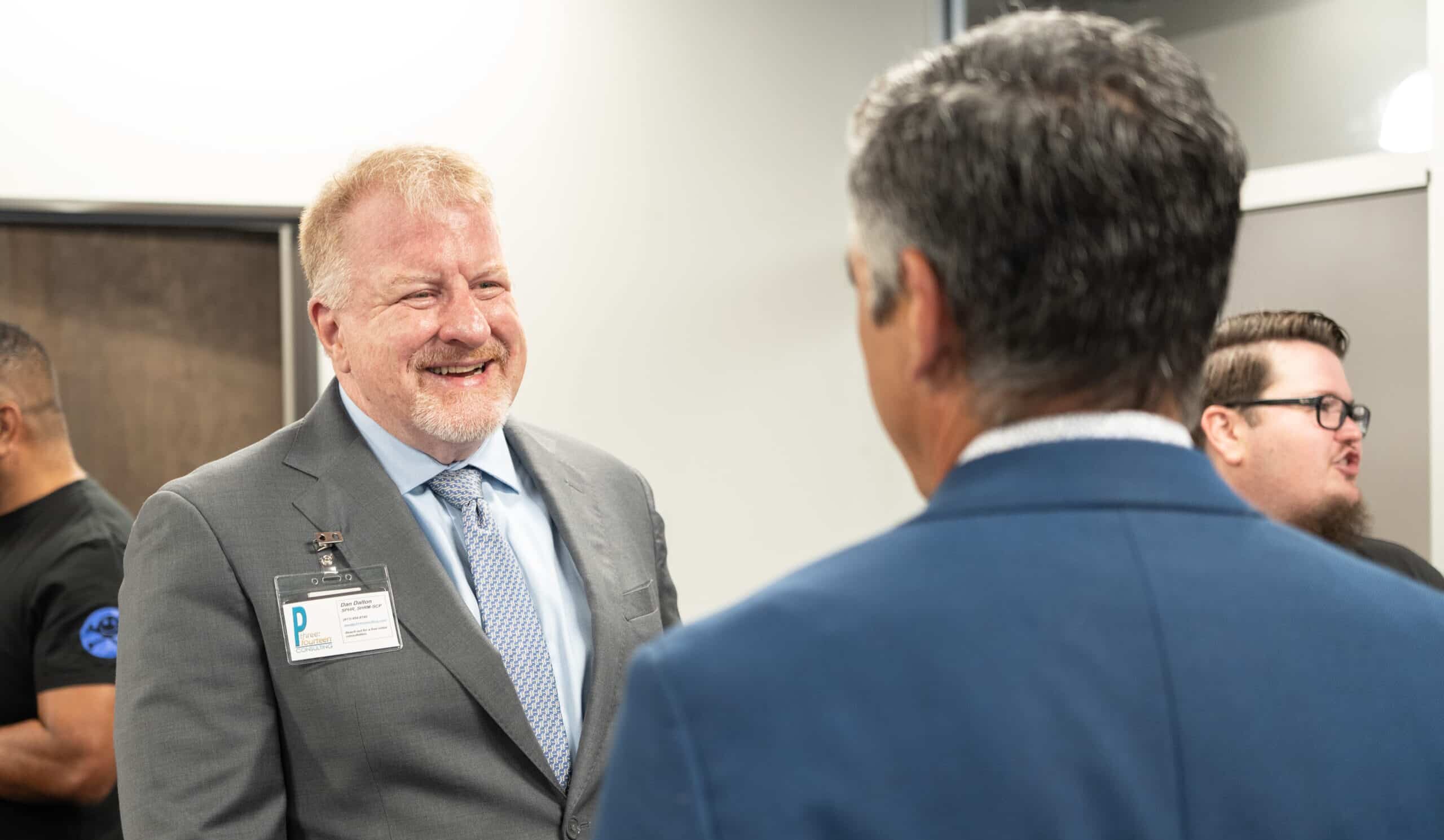 Leadership Through Genuine Connection ‣ P3:14 Consulting Man in suit smiling while networking at business event