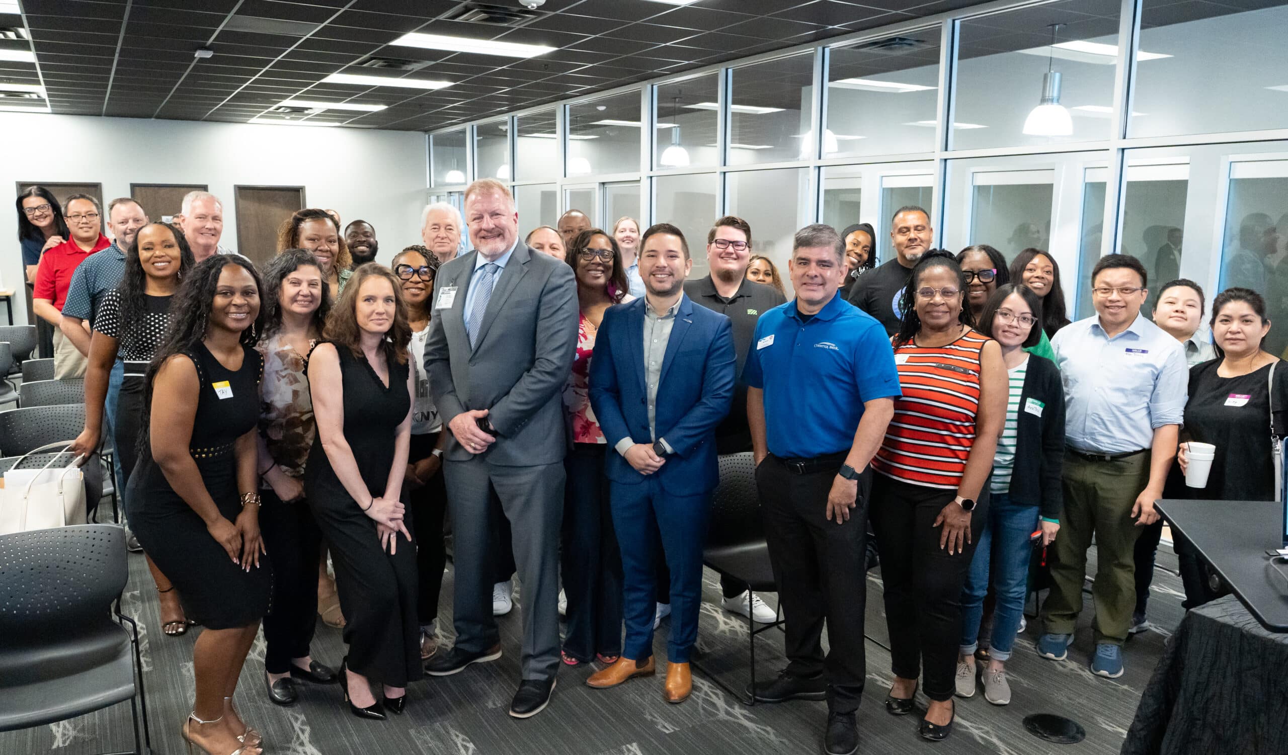 Dan B. Dalton of P3:14 Consulting poses with a diverse group of smiling business professionals during a networking event in a modern office conference space.