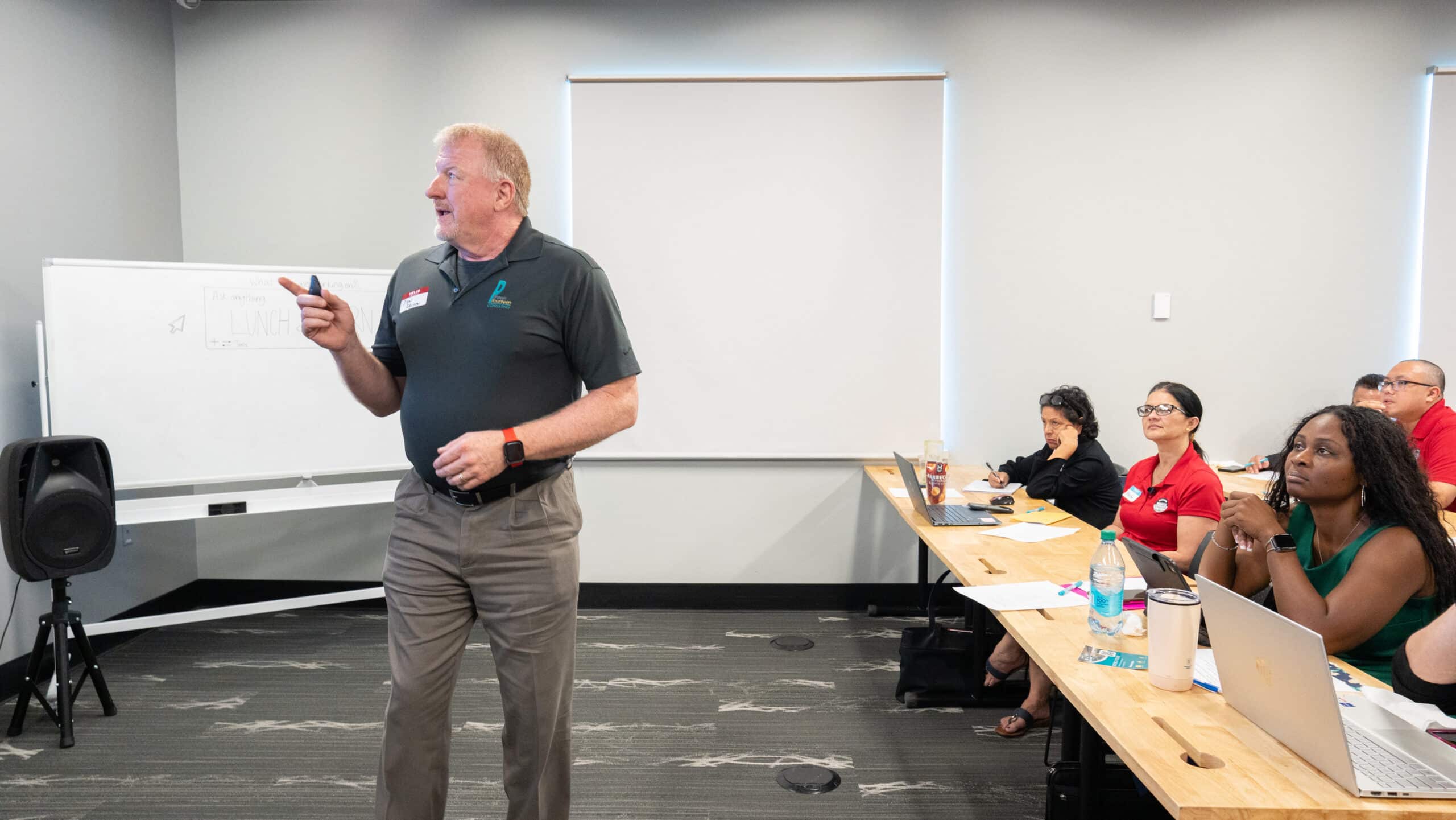 Man in polo shirt leading presentation with audience listening attentively